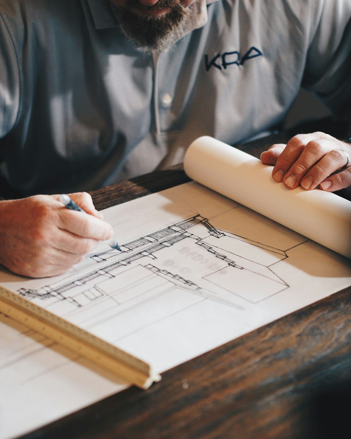 Architect reviewing building blueprints at wooden desk with rolled plans