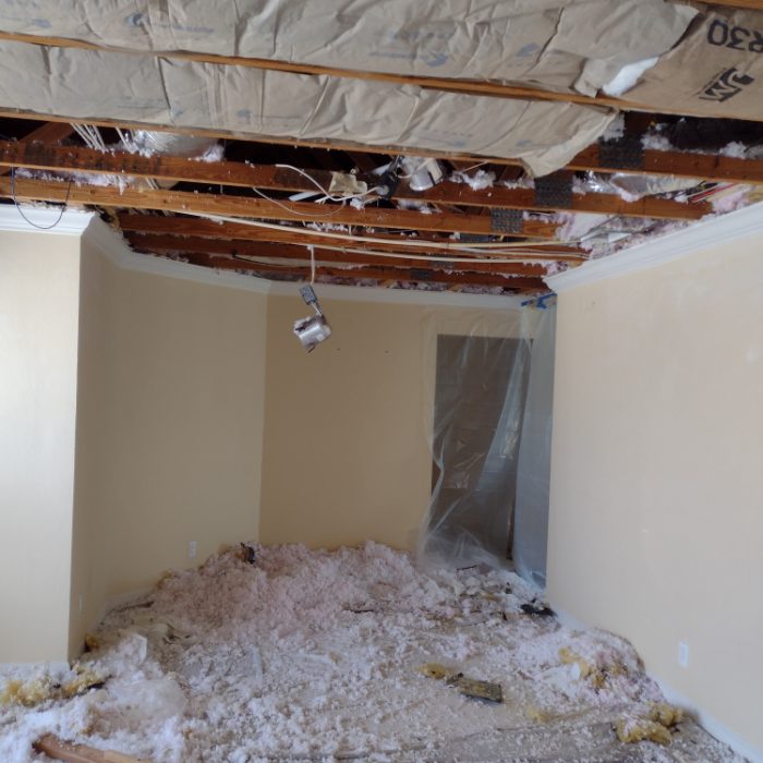 Interior room with exposed wooden ceiling beams and debris pile on floor during renovation
