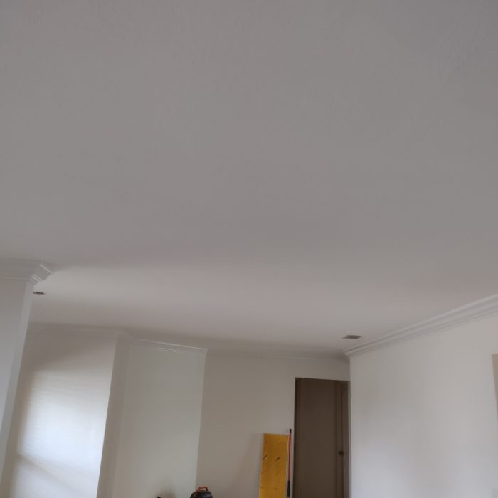 Empty room interior with white walls, ceiling, and brown door frame