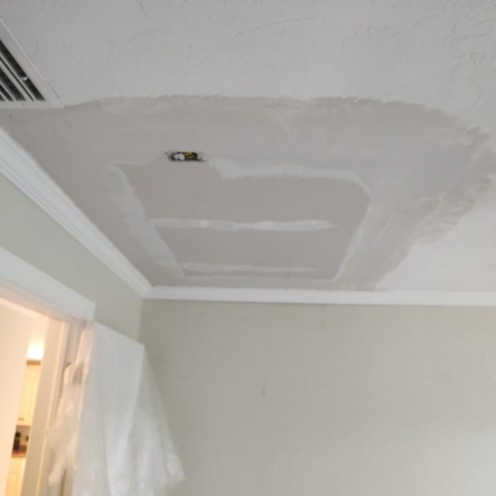 Interior drywall ceiling with recessed lighting fixture installation and white painted finish