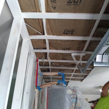 Interior ceiling under construction with white drywall framing, cardboard sheathing, and blue plumbing pipes