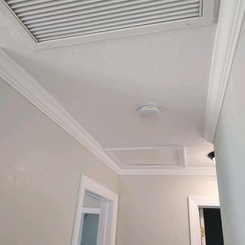White hallway ceiling with recessed lighting and return air vent
