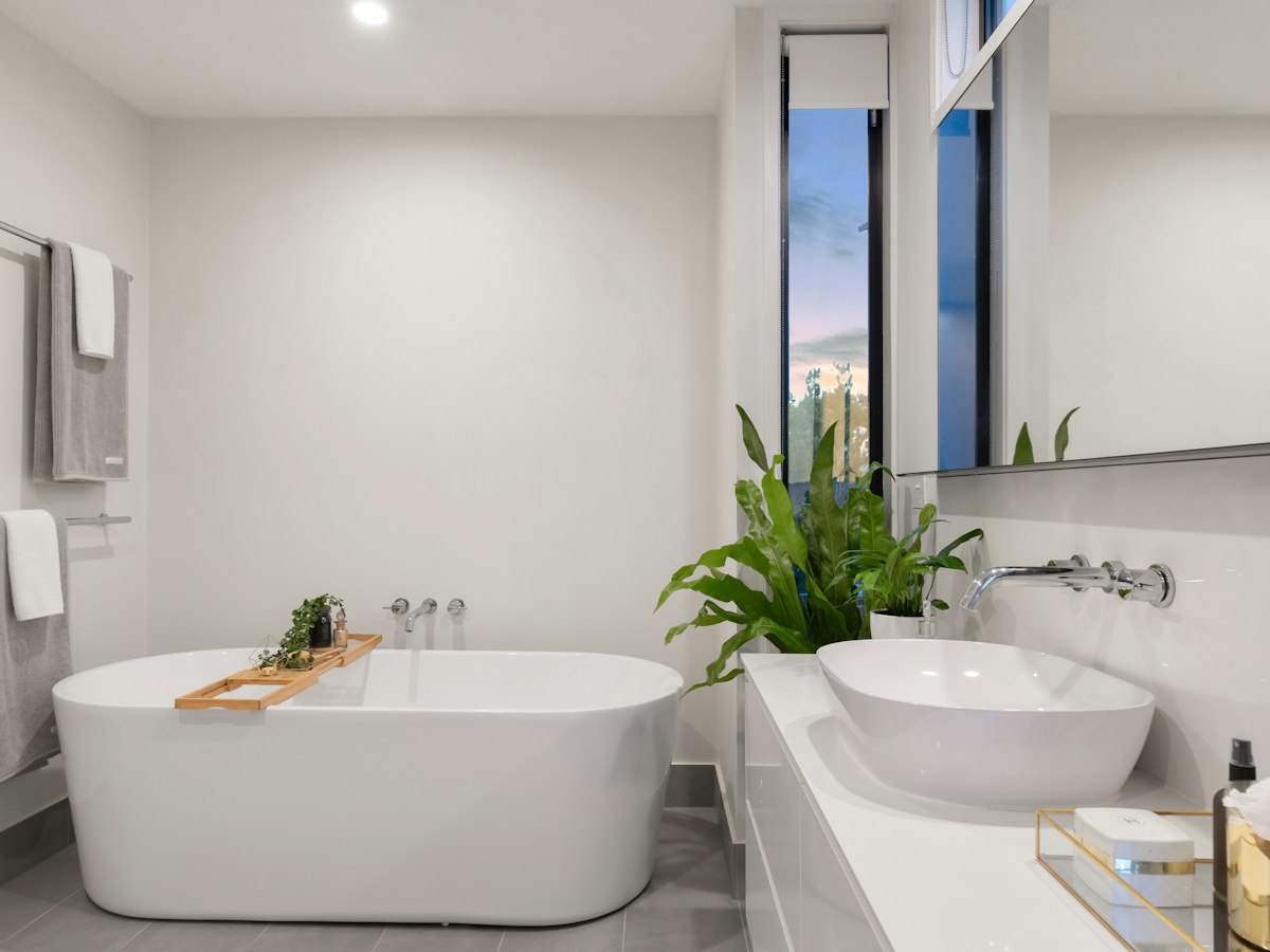 Modern luxury bathroom with white freestanding tub, vessel sink, and tall windows overlooking mountains