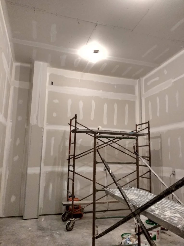 Interior drywall construction with metal scaffolding and ceiling light fixture